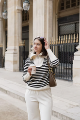 a lady in a striped zip-up sweater and a pair of white cordury like pants